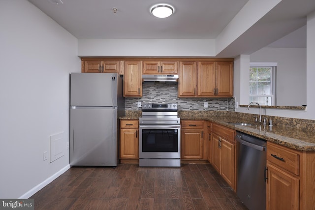 kitchen with decorative backsplash, dark stone counters, stainless steel appliances, sink, and dark hardwood / wood-style floors