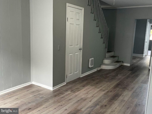 stairway with heating unit, crown molding, and wood-type flooring