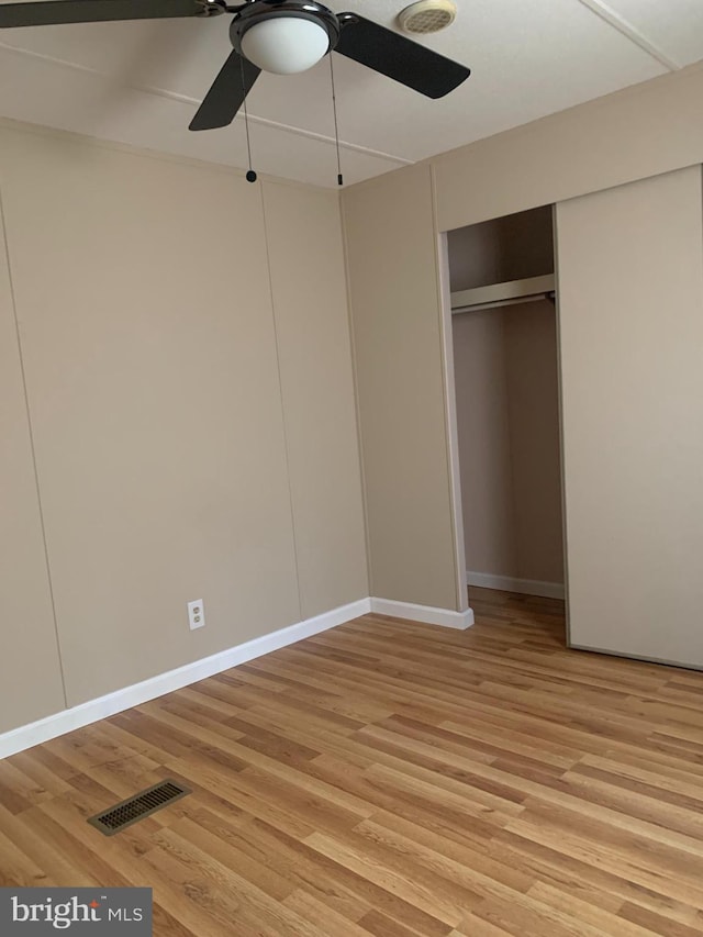 unfurnished bedroom with ceiling fan, a closet, and light wood-type flooring