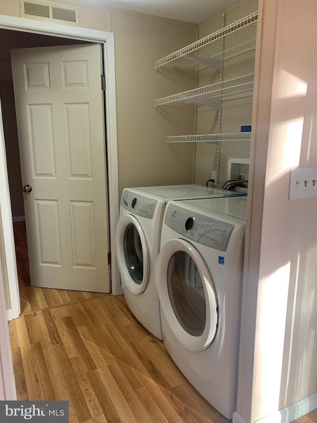 washroom featuring washing machine and dryer and light wood-type flooring