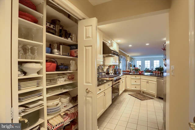 kitchen with kitchen peninsula, white cabinetry, light tile patterned flooring, and stainless steel appliances