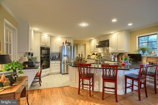 kitchen featuring black appliances, white cabinetry, and range hood