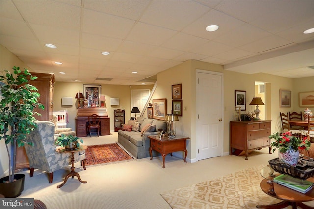 living room with carpet and a paneled ceiling