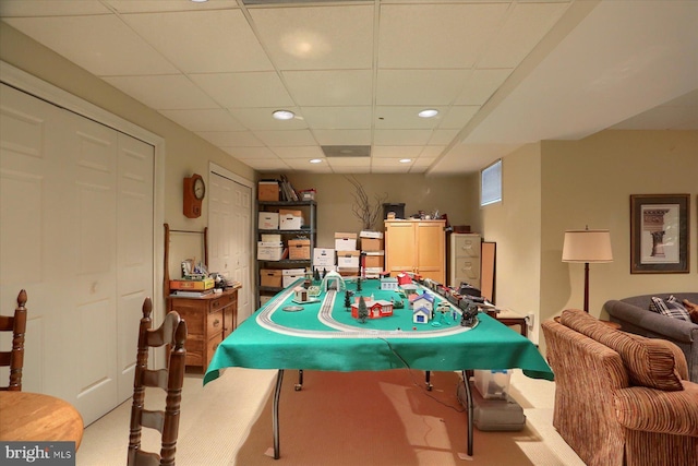 game room with a paneled ceiling and light colored carpet