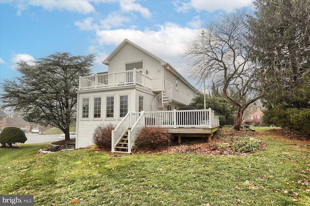 rear view of house with a lawn, a wooden deck, and a balcony