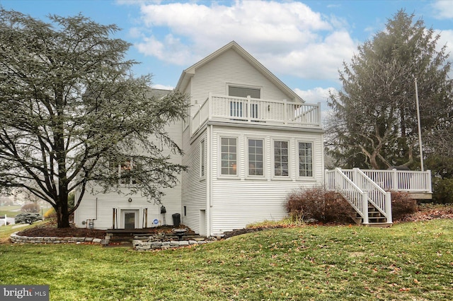 back of property featuring a balcony and a lawn