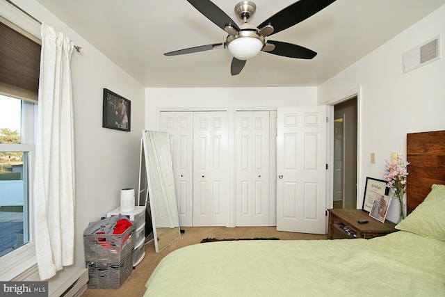 bedroom featuring ceiling fan, light colored carpet, and multiple closets