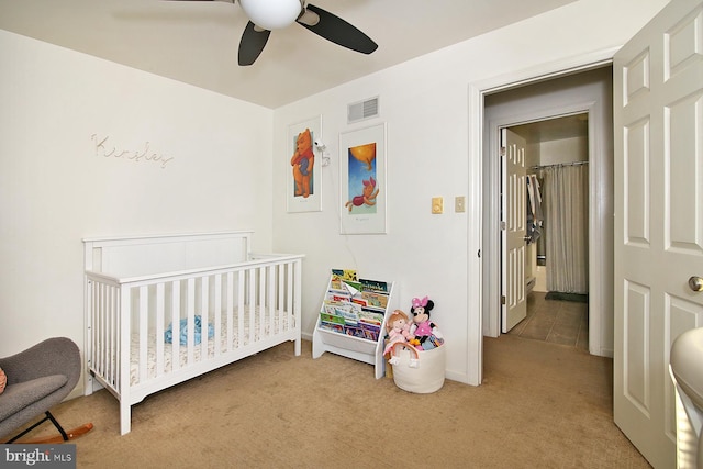 bedroom featuring carpet floors, a nursery area, and ceiling fan