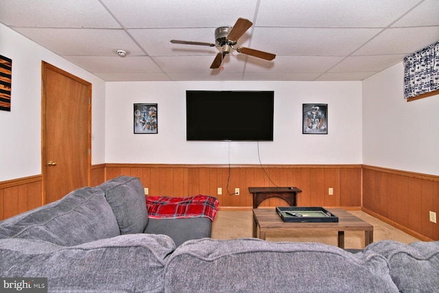 living room featuring wooden walls, a drop ceiling, and carpet floors