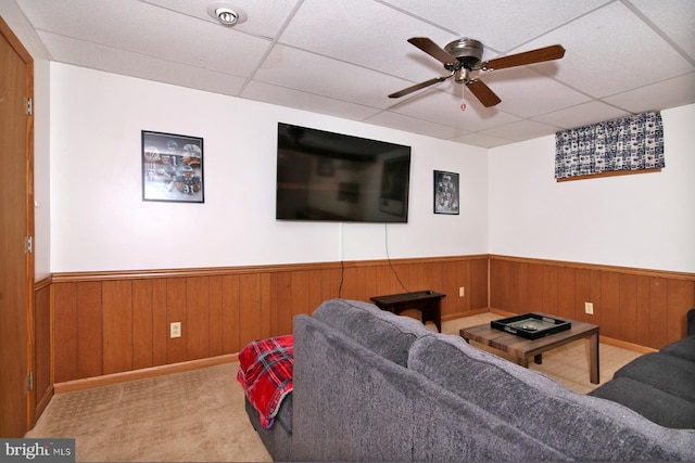 living room with light carpet, a drop ceiling, and wood walls