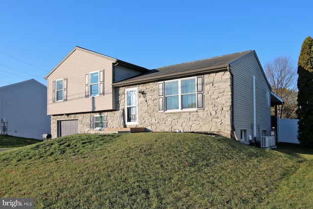 tri-level home featuring cooling unit, a garage, and a front yard