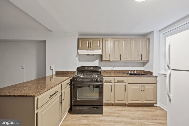 kitchen with kitchen peninsula, light hardwood / wood-style floors, black gas range oven, dark stone countertops, and white fridge