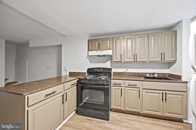 kitchen with dark stone counters, sink, light wood-type flooring, kitchen peninsula, and black range with gas cooktop