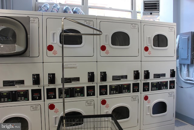 clothes washing area featuring electric panel, stacked washer and dryer, and washing machine and clothes dryer