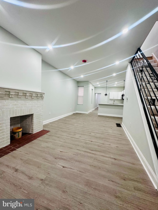 unfurnished living room featuring sink, light wood-type flooring, and a fireplace