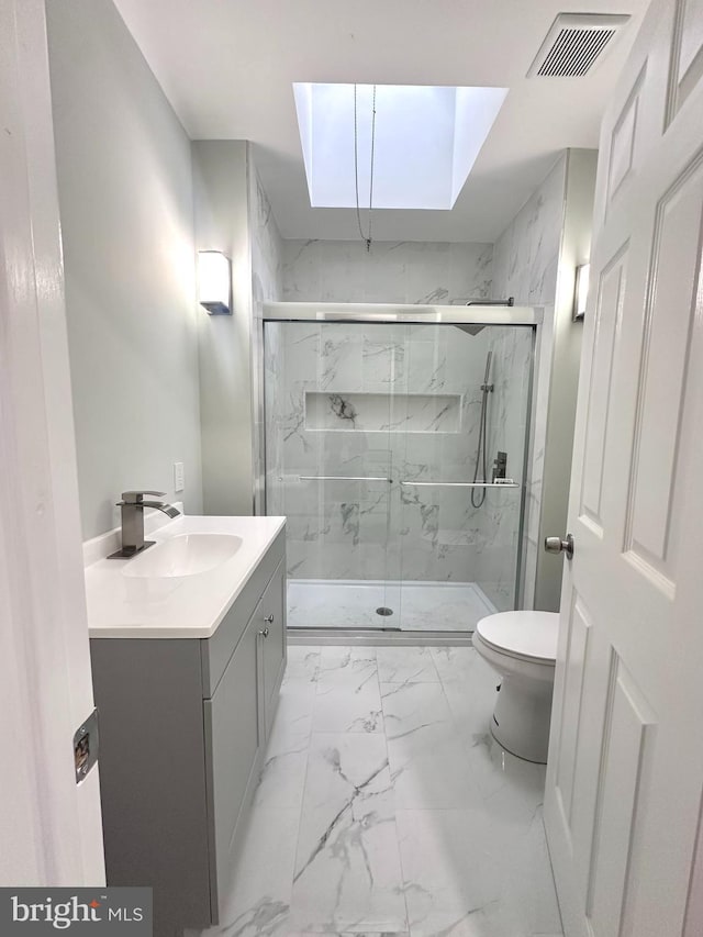 bathroom with vanity, a skylight, toilet, and an enclosed shower