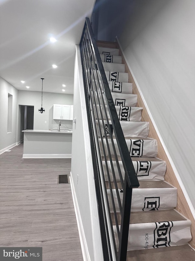 stairway with sink and wood-type flooring