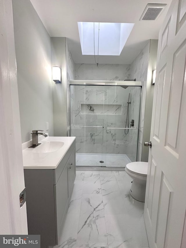 bathroom with a skylight, vanity, an enclosed shower, and toilet