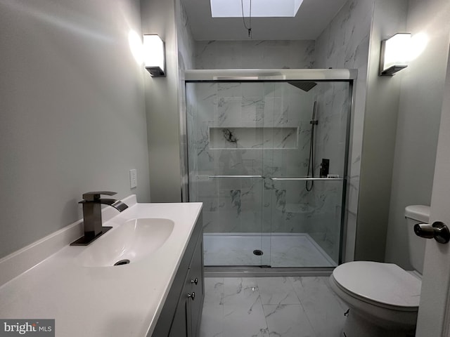 bathroom featuring vanity, toilet, a shower with shower door, and a skylight