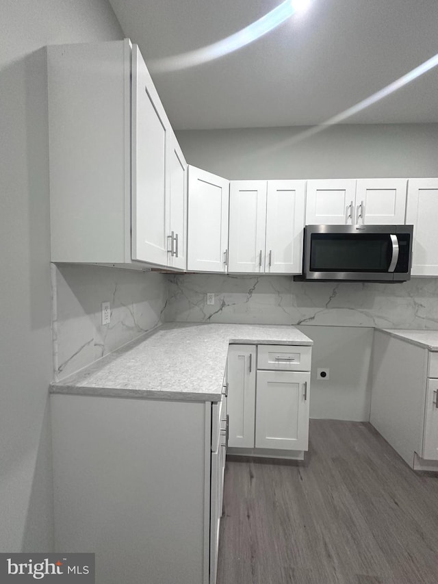 kitchen featuring decorative backsplash, wood-type flooring, and white cabinetry