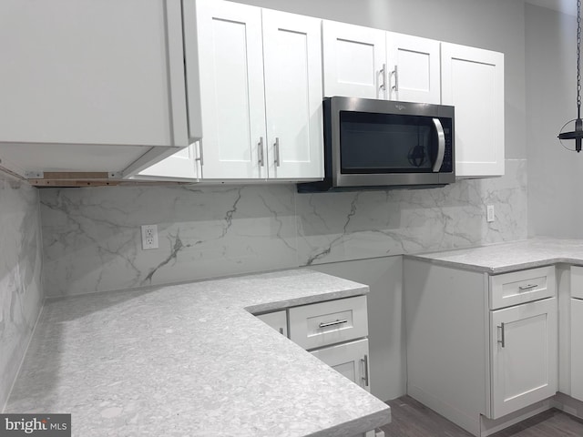 kitchen with white cabinets, decorative light fixtures, dark hardwood / wood-style floors, and tasteful backsplash