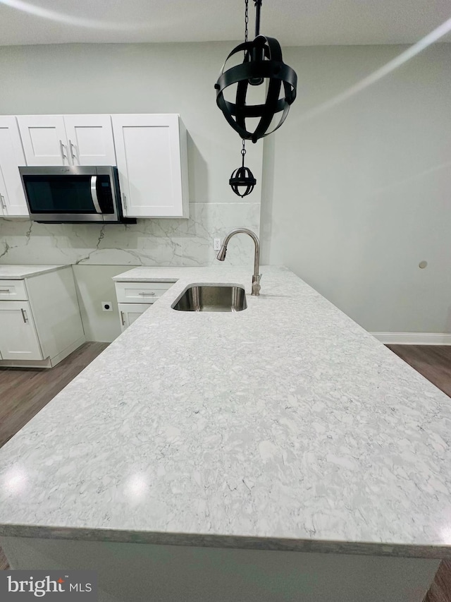 kitchen with white cabinetry, sink, hanging light fixtures, dark hardwood / wood-style floors, and backsplash