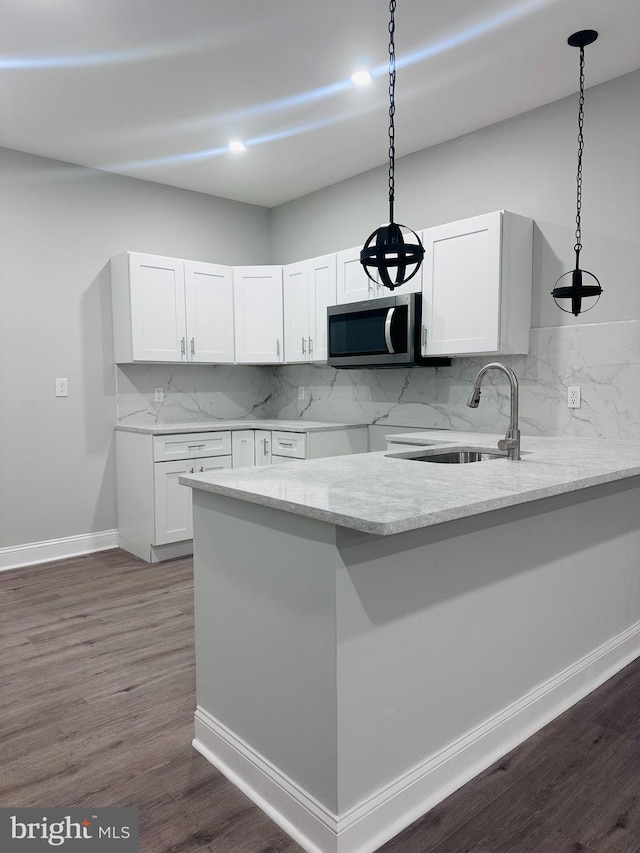 kitchen with dark wood-type flooring, white cabinets, sink, hanging light fixtures, and tasteful backsplash