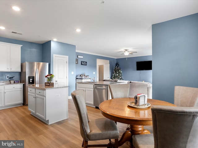 dining area with light hardwood / wood-style floors, ceiling fan, ornamental molding, and sink