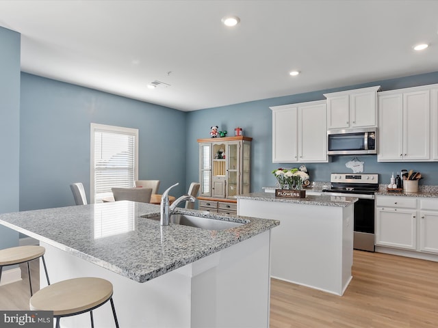 kitchen featuring sink, white cabinetry, an island with sink, and appliances with stainless steel finishes