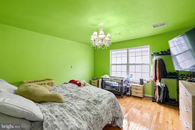 bedroom featuring light wood-type flooring and a notable chandelier