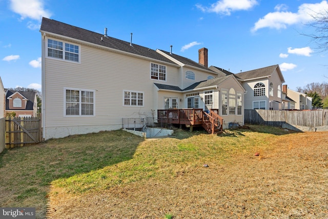 rear view of property with a deck, a lawn, and a fenced backyard