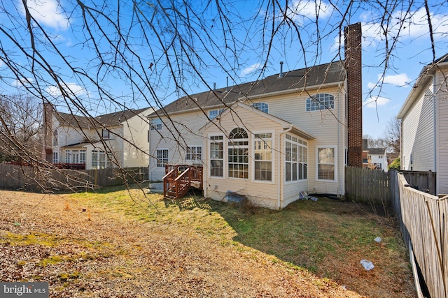 back of property with a sunroom, a fenced backyard, a lawn, and a chimney