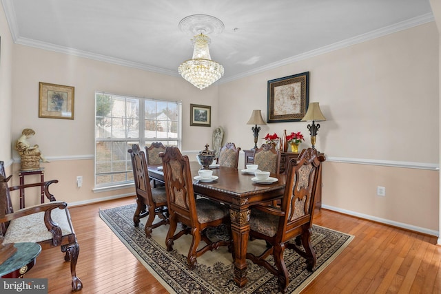 dining space with a chandelier, light wood-type flooring, and crown molding