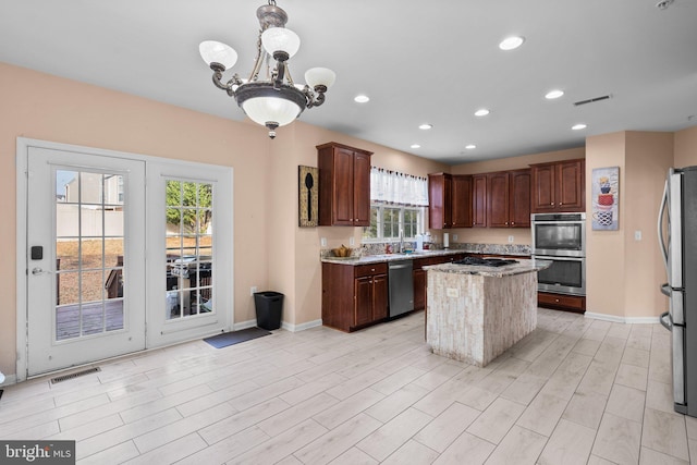 kitchen featuring a wealth of natural light, a center island, a chandelier, and appliances with stainless steel finishes