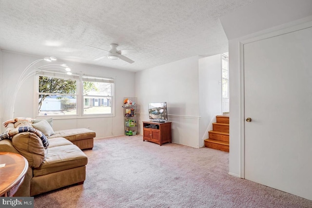 living area featuring light carpet, ceiling fan, and a textured ceiling