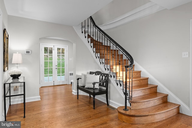 stairway featuring french doors, ornamental molding, and hardwood / wood-style flooring