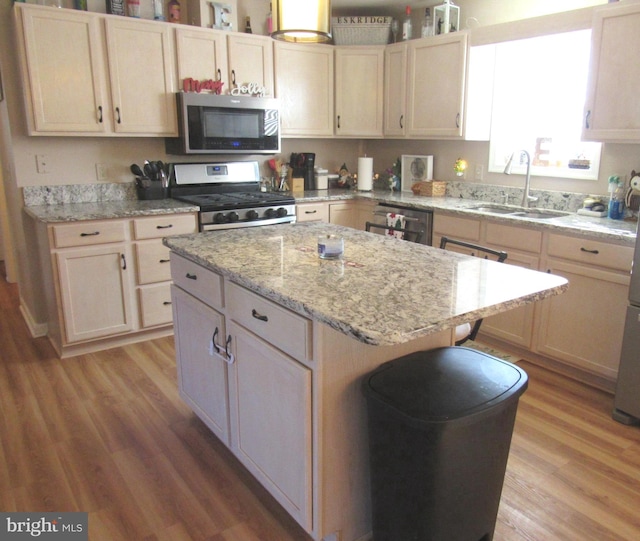 kitchen with appliances with stainless steel finishes, light hardwood / wood-style flooring, a kitchen island, and sink