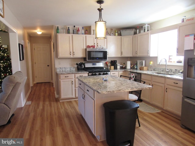 kitchen with sink, light hardwood / wood-style floors, decorative light fixtures, a kitchen island, and stainless steel appliances