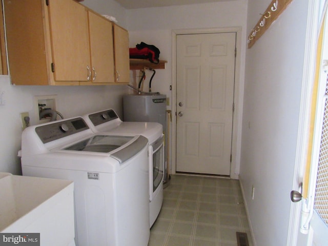 clothes washing area featuring washing machine and clothes dryer, water heater, sink, and cabinets