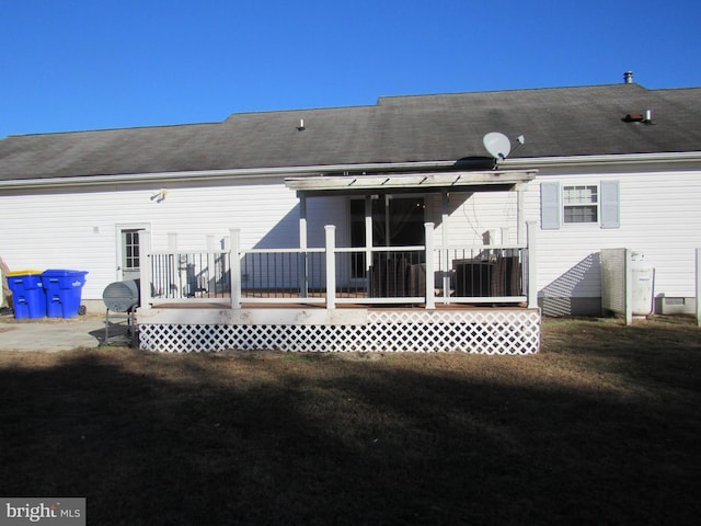 rear view of house featuring a wooden deck and a yard