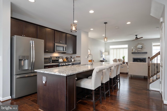 kitchen with sink, hanging light fixtures, a center island with sink, and appliances with stainless steel finishes