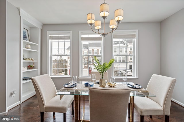 dining room with built in features, plenty of natural light, dark hardwood / wood-style floors, and an inviting chandelier