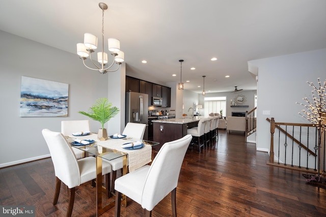 dining area with sink, dark wood-type flooring, and a notable chandelier