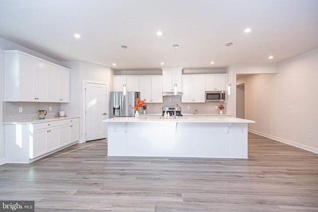 kitchen with decorative light fixtures, white cabinetry, an island with sink, and appliances with stainless steel finishes