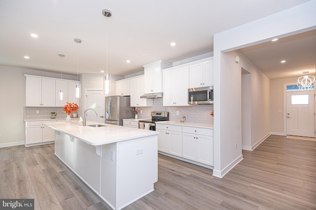 kitchen with a center island with sink, hanging light fixtures, light hardwood / wood-style flooring, appliances with stainless steel finishes, and white cabinetry