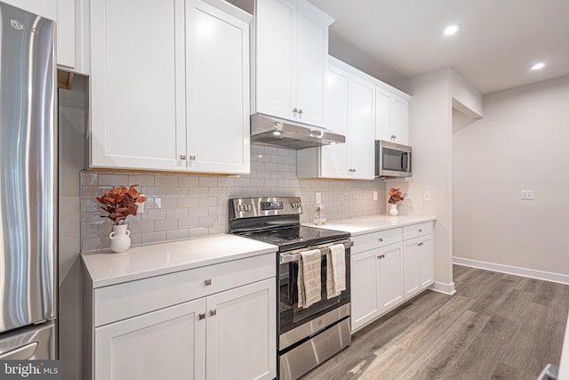 kitchen with white cabinets, light hardwood / wood-style floors, backsplash, and appliances with stainless steel finishes