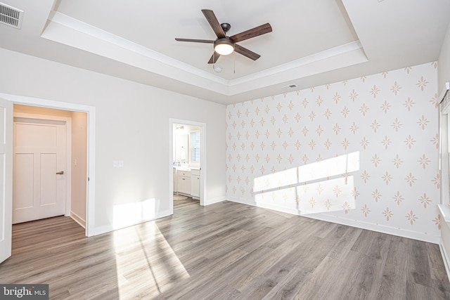 unfurnished room featuring hardwood / wood-style flooring, a raised ceiling, and ceiling fan