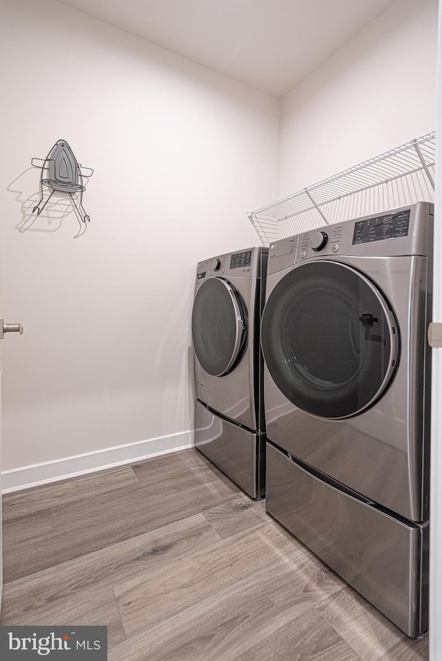 clothes washing area featuring hardwood / wood-style flooring and washer and dryer