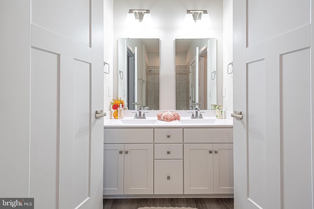 bathroom featuring hardwood / wood-style floors, vanity, and a tile shower