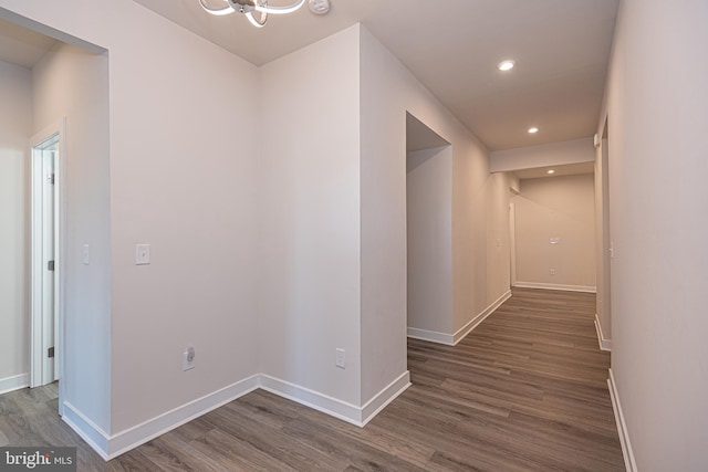 corridor with dark wood-type flooring and a chandelier